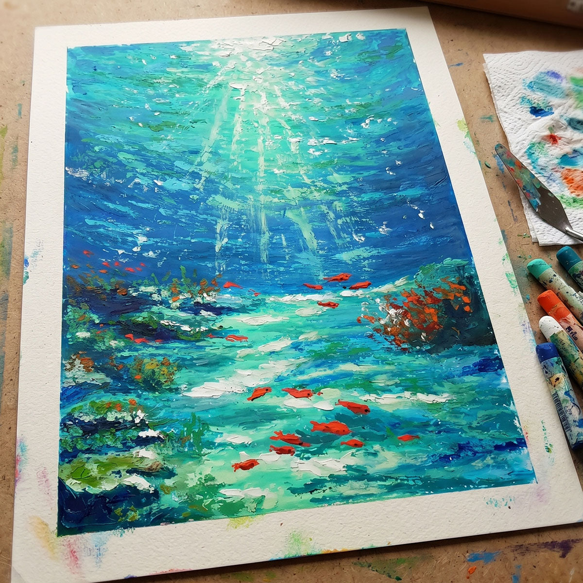 Handcrafted oil pastel painting of a sunlit underwater scene with orange fish and light beams through turquoise water.