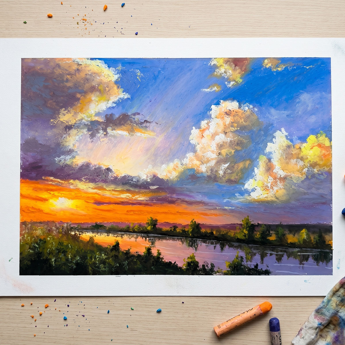 Handcrafted oil pastel painting of a radiant sunset over a calm river with dramatic textured clouds and golden reflections.