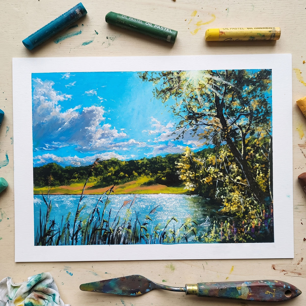 andcrafted oil pastel painting of a sunny lake with sparkling water, fluffy clouds, and sunlight shining through trees.